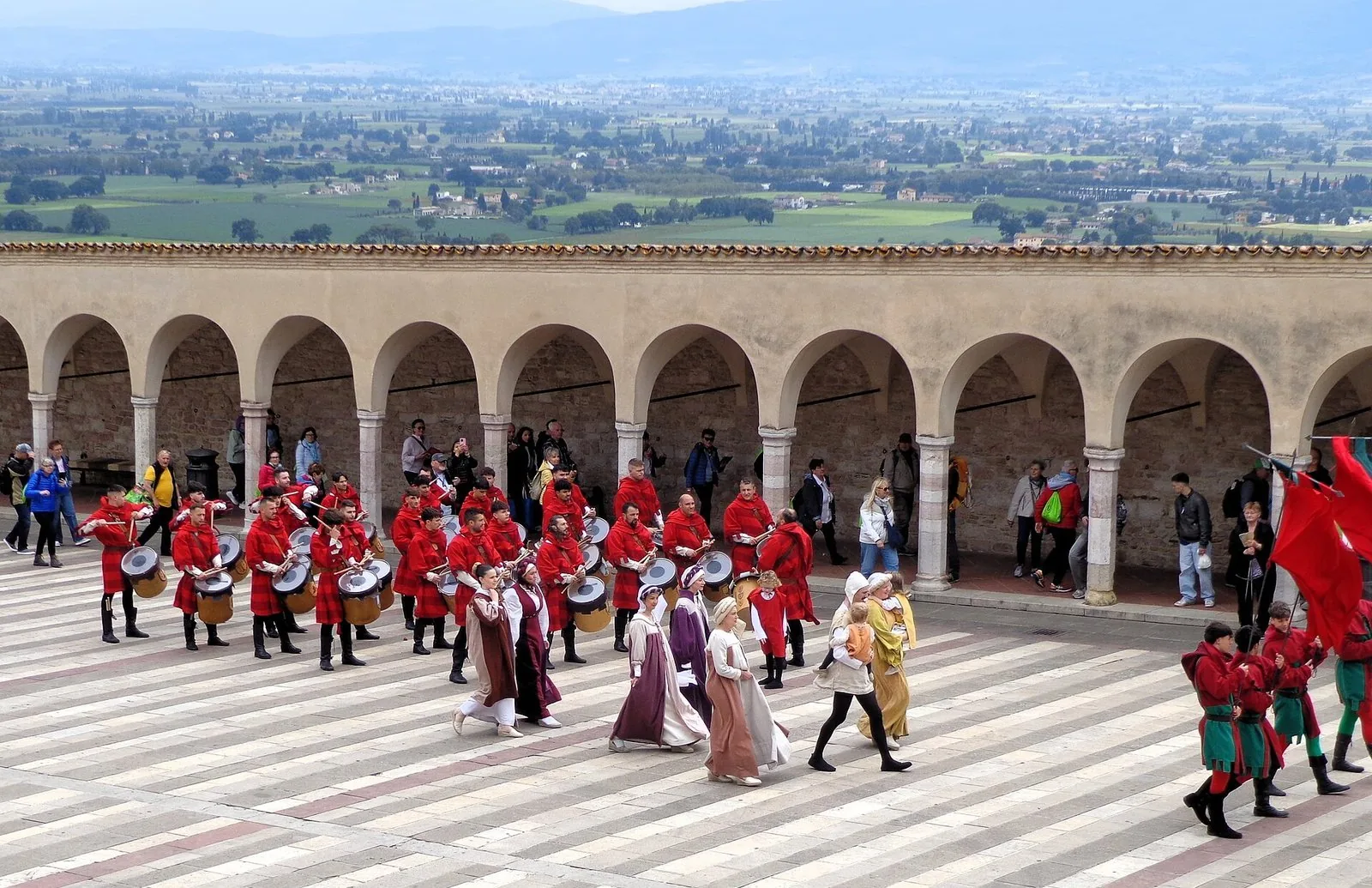 Tamburini e dame in costume medievale sfilano davanti al porticato di San Francesco durante il Calendimaggio di Assisi